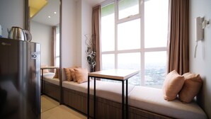 A modern kitchen with a built-in bench seating area, a table, and a view of the city through large windows. - Homey Studio At Taman Melati Surabaya Apartment (Surabaya)
