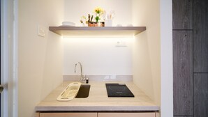 A bathroom with a countertop, a sink, a faucet, a shelf with toiletries, and a small plant. - Homey Studio At Taman Melati Surabaya Apartment (Surabaya)
