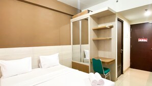 Una habitación de hotel con cama, una silla verde, un armario y una puerta.