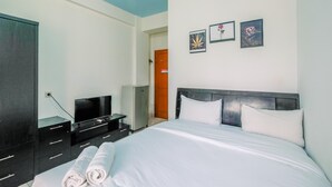 A hotel room with a bed, a TV, a desk, and a wardrobe. - Cozy Living Studio Apartment At Margonda Residence 1 (Depok)