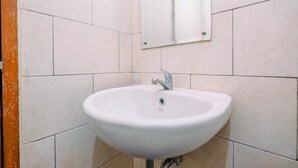 A white bathroom sink with a mirror above it, mounted on a tiled wall. - Cozy Living Studio Apartment At Margonda Residence 1 (Depok)