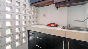 A kitchen with a tiled backsplash, a sink, and cabinets. - Cozy Living Studio Apartment At Margonda Residence 1 (Depok)