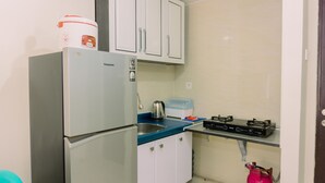 A compact kitchen with a refrigerator, a gas stove, a sink, and cabinets. - Modern Look And Homey 2Br At Great Western Resort Apartment (Tangerang)