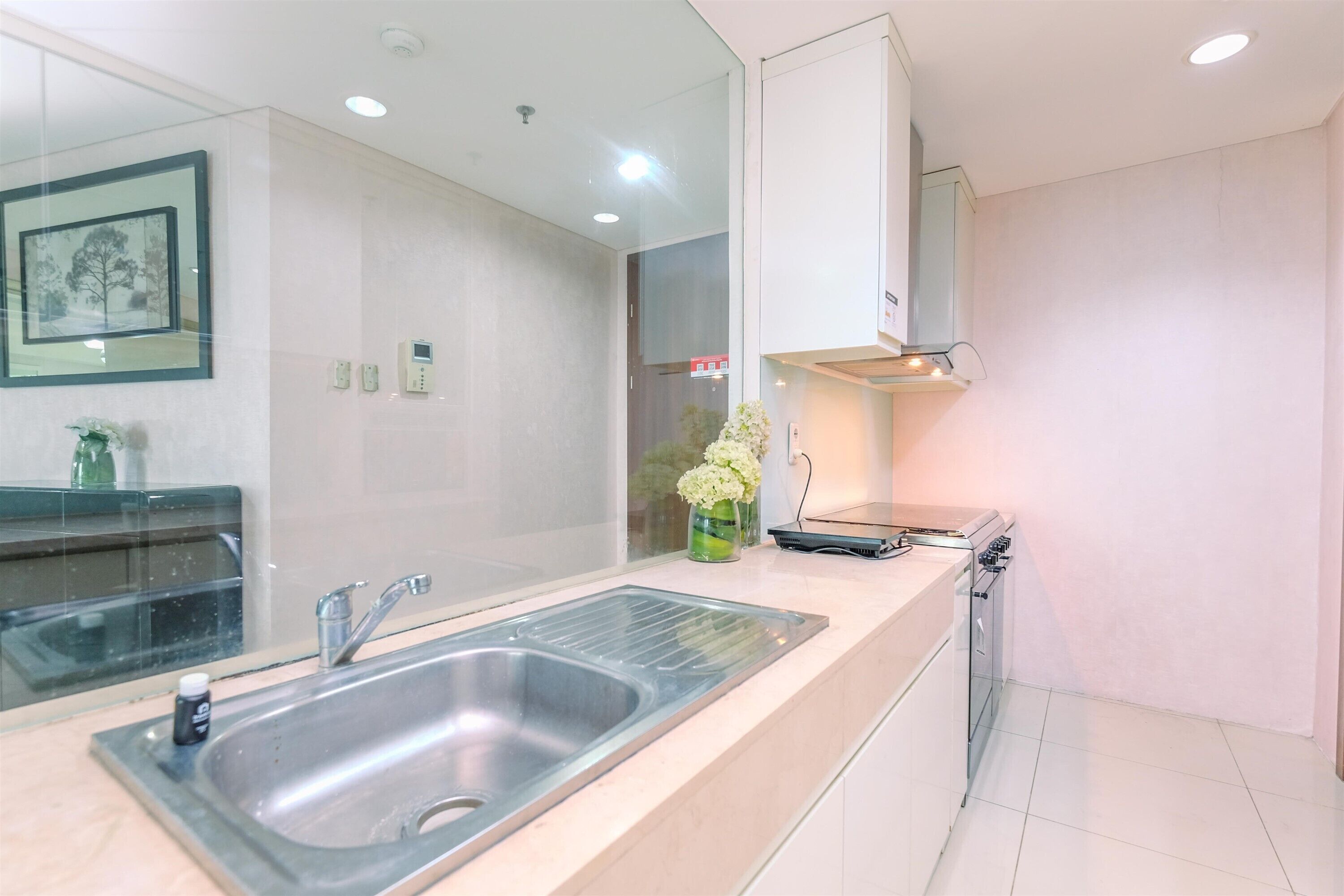 A modern kitchen with a stainless steel sink, a stove, and a microwave. There is a vase with flowers on the counter.