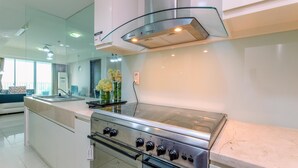 A modern kitchen with a stainless steel stove, a glass backsplash, and a built-in oven. - Spacious 3Br At Kemang Village Apartment (Jakarta)
