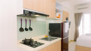 A compact kitchenette with a gas stove, a sink, and a refrigerator. - Simply Look And Homey Studio Apartment At M-Town Residence (Gading Serpong)