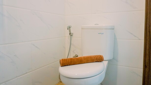 A bathroom with a toilet, a shower, and a towel. - Minimalist And Nice Studio At Sky House Alam Sutera Apartment (Tangerang)