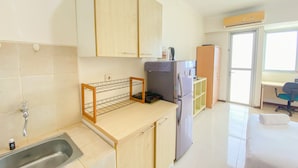Una cocina compacta con pileta, muebles de madera, refrigerador y una pequeña mesada.