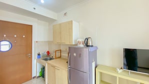 Una cocina compacta con refrigerador, lavamanos y una pequeña encimera.