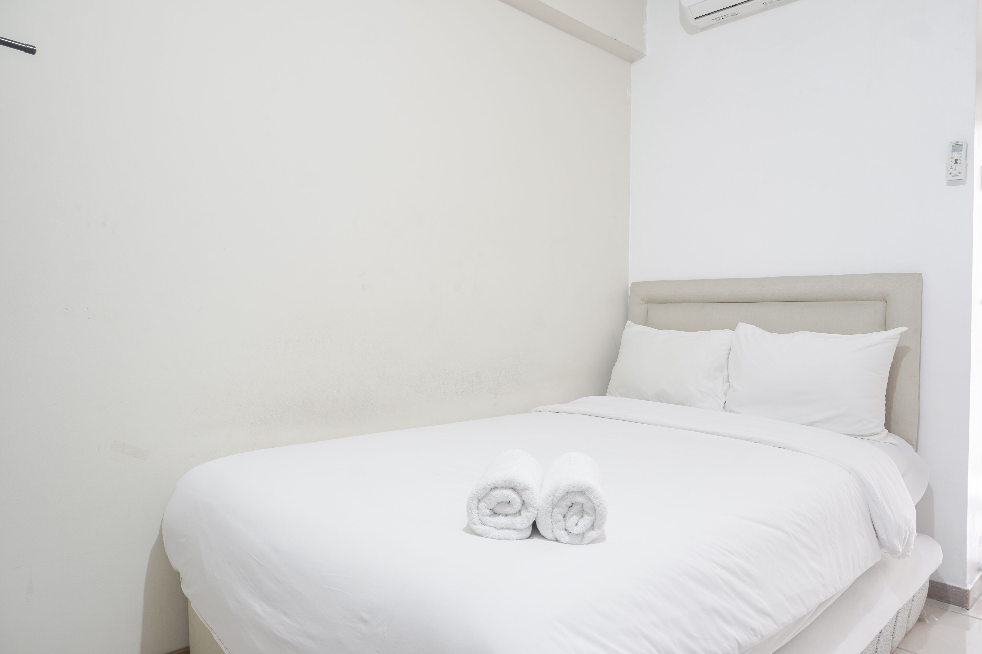 Un lit bien fait, avec du linge de lit blanc et deux serviettes enroulées posées au pied du lit.