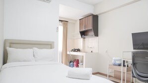 Une chambre d’hôtel comprenant un lit, un bureau avec une chaise, une télévision et un coin cuisine.