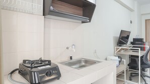 Une cuisine équipée d’une cuisinière à gaz, d’un évier et d’un bureau avec un ordinateur et une chaise.