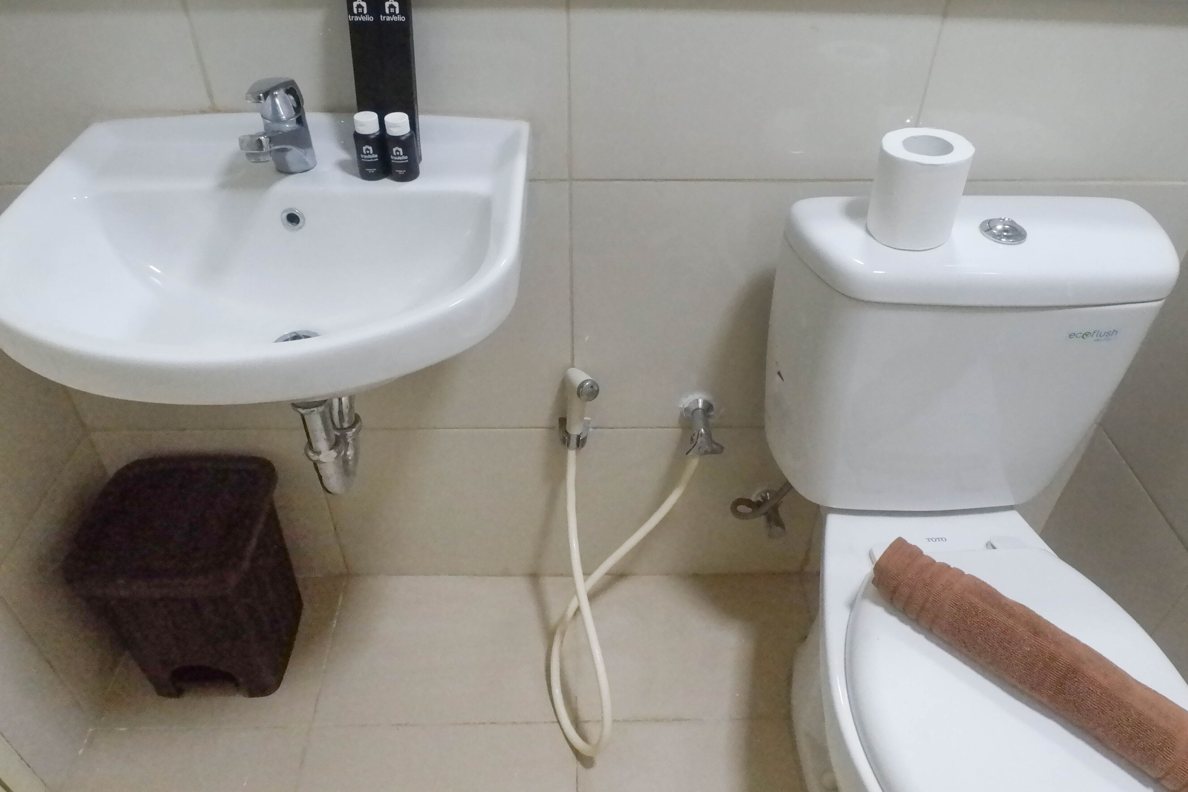 A bathroom with a white sink, toilet, and a small stool.