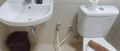 A bathroom with a white sink, toilet, and a small stool.