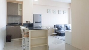 A modern kitchen with a central island, bar stools, and a built-in refrigerator.