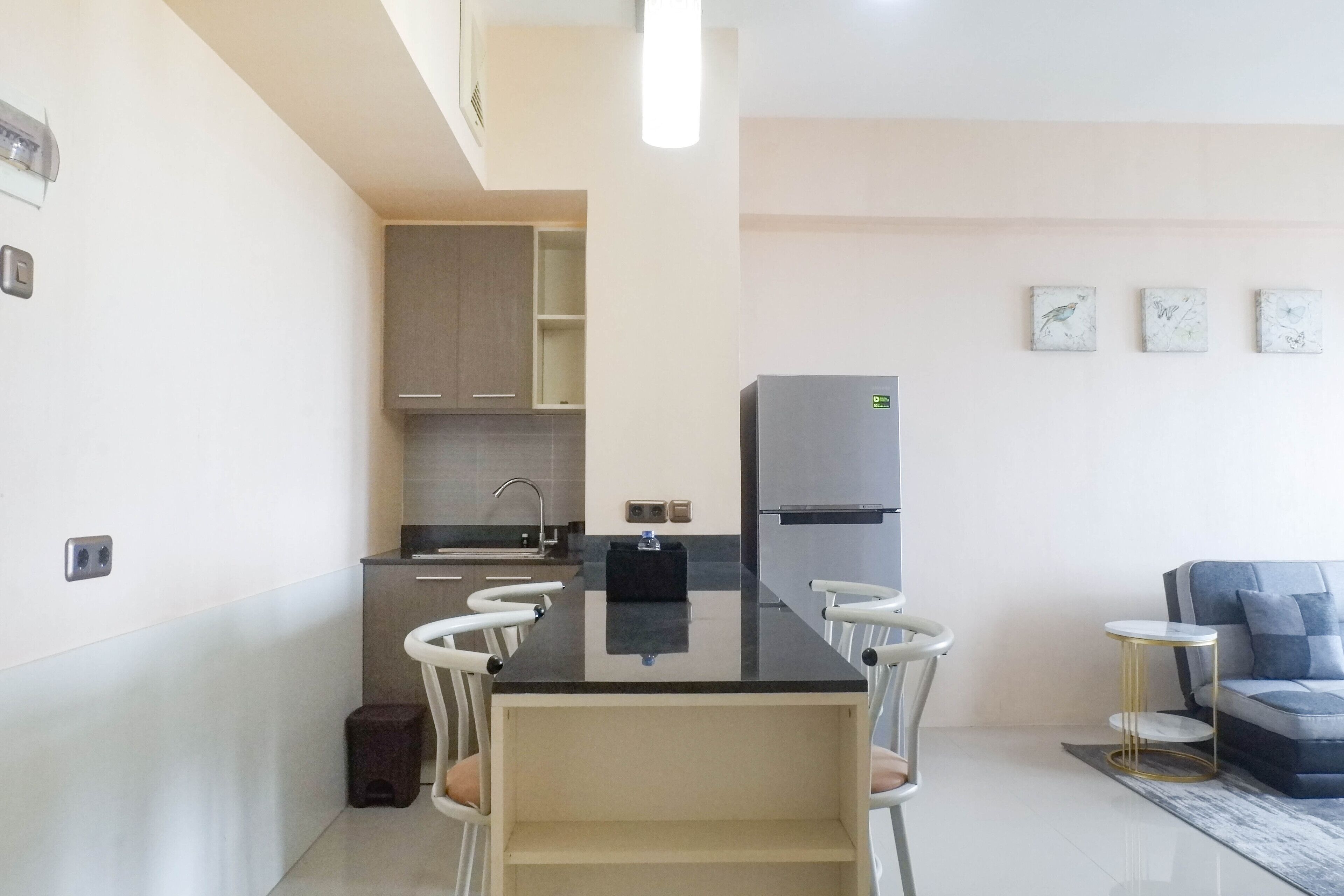 A modern kitchen with a black countertop, white chairs, a grey sofa, and a small round table.