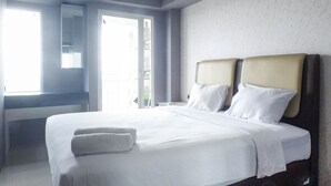A hotel room with a large bed, a bedside table, a mirror, and a window.