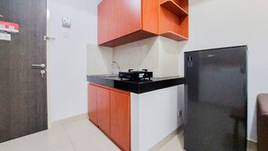 Una cocina compacta con armarios de madera, un refrigerador negro y una encimera con un lavamanos.