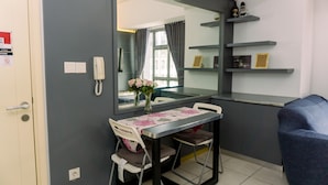 A compact room with a dining table, chairs, a mirror, a phone, and a blue sofa. - Comfort 1Br At 32Th Floor Apartment M-Town Residence (Gading Serpong)