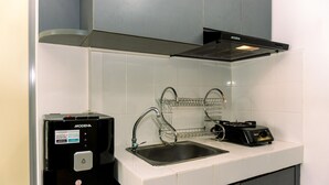 A modern kitchen with a stainless steel sink, a coffee machine, and a range hood. - Comfort 1Br At 32Th Floor Apartment M-Town Residence (Gading Serpong)