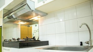 A kitchen with a stainless steel sink, a gas stove, and a range hood above the stove. - Homey And Cozy Stay Studio At Margonda Residence 2 Apartment (Depok)