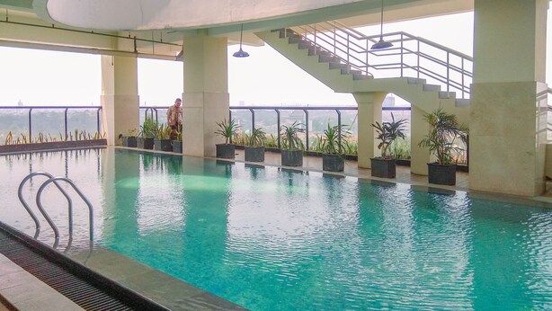 Piscina interior con agua cristalina, rodeada de plantas en macetas y una escalera que conduce a un nivel superior.