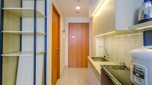 Une petite cuisine étroite avec une porte en bois, un évier et une bouilloire posée sur le plan de travail.