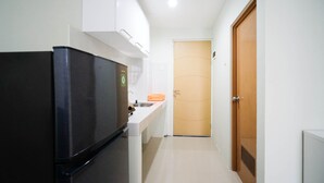 A compact kitchen with a refrigerator, sink, and a wooden door. - Best Choice And Cozy Living At 2Br At Bale Hinggil Apartment (Surabaya)