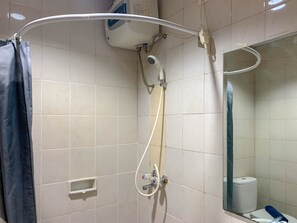 Bathroom features a shower area with a wall-mounted showerhead and a small shelf for toiletries.