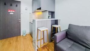 A compact living space with a kitchenette, a sofa, and two stools. - Nice And Simply Look 2Br At Serpong Garden Apartment (Cisauk)