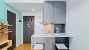 A compact kitchen with a marble countertop, two stools, and a grey cabinet. - Nice And Simply Look 2Br At Serpong Garden Apartment (Cisauk)