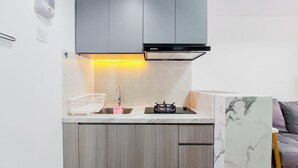 A compact kitchen with grey cabinets, a stainless steel range hood, a gas stove, and a white marble backsplash. - Nice And Simply Look 2Br At Serpong Garden Apartment (Cisauk)