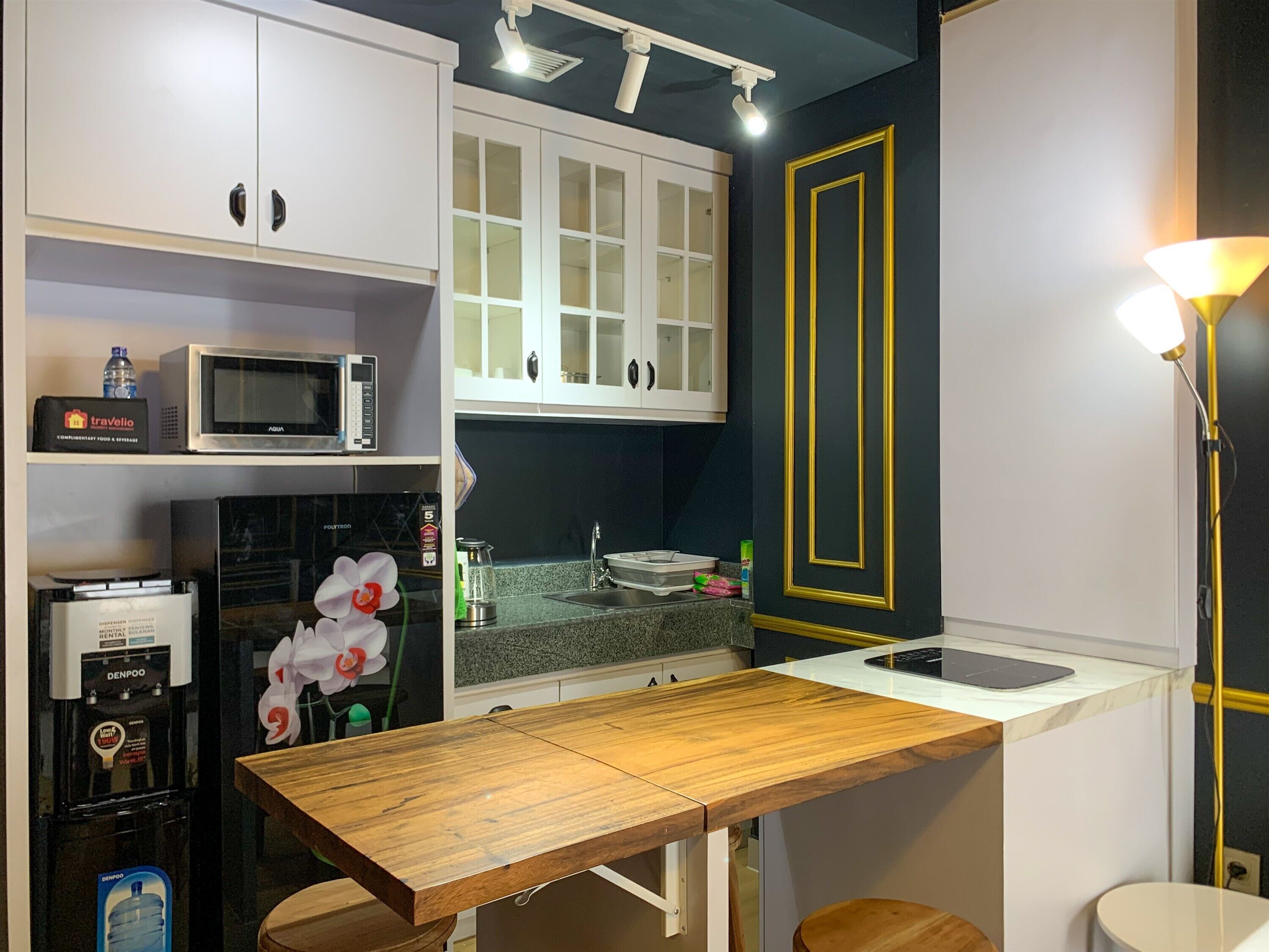 A compact kitchen with white cabinets, a microwave, a water dispenser, and a sink.