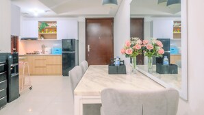 A modern kitchen with a marble countertop, a dining table with chairs, and a large mirror reflecting the room. - Comfortable 2Br At Apartment Casa Grande Residence (Jakarta)