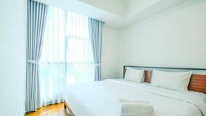 A hotel room with a large bed, white linens, and a wooden headboard. - Comfortable 2Br At Apartment Casa Grande Residence (Jakarta)