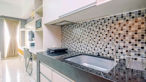 A modern kitchen with a black countertop, stainless steel sink, and a tiled backsplash. - Good Location And Cozy Studio Margonda Residence 2 Apartment (Depok)