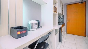 A kitchenette with a microwave, kettle, and a trash bin labeled 'Travelio'. - Good Location And Cozy Studio Margonda Residence 2 Apartment (Depok)