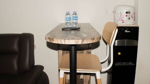 A small round table with two water bottles, a remote control, and a coffee maker. - Comfort Living 3Br At Springlake Summarecon Bekasi Apartment (Bekasi)