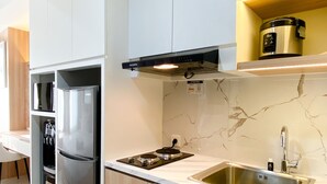 A modern kitchen with a stainless steel refrigerator, a built-in oven, a sink, and a coffee maker on a shelf. - Comfortable Stay Studio At Pollux Chadstone Apartment (Cikarang)