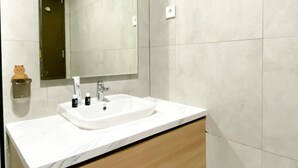 A bathroom with a white sink, a mirror, and a beige cabinet. - Comfortable Stay Studio At Pollux Chadstone Apartment (Cikarang)