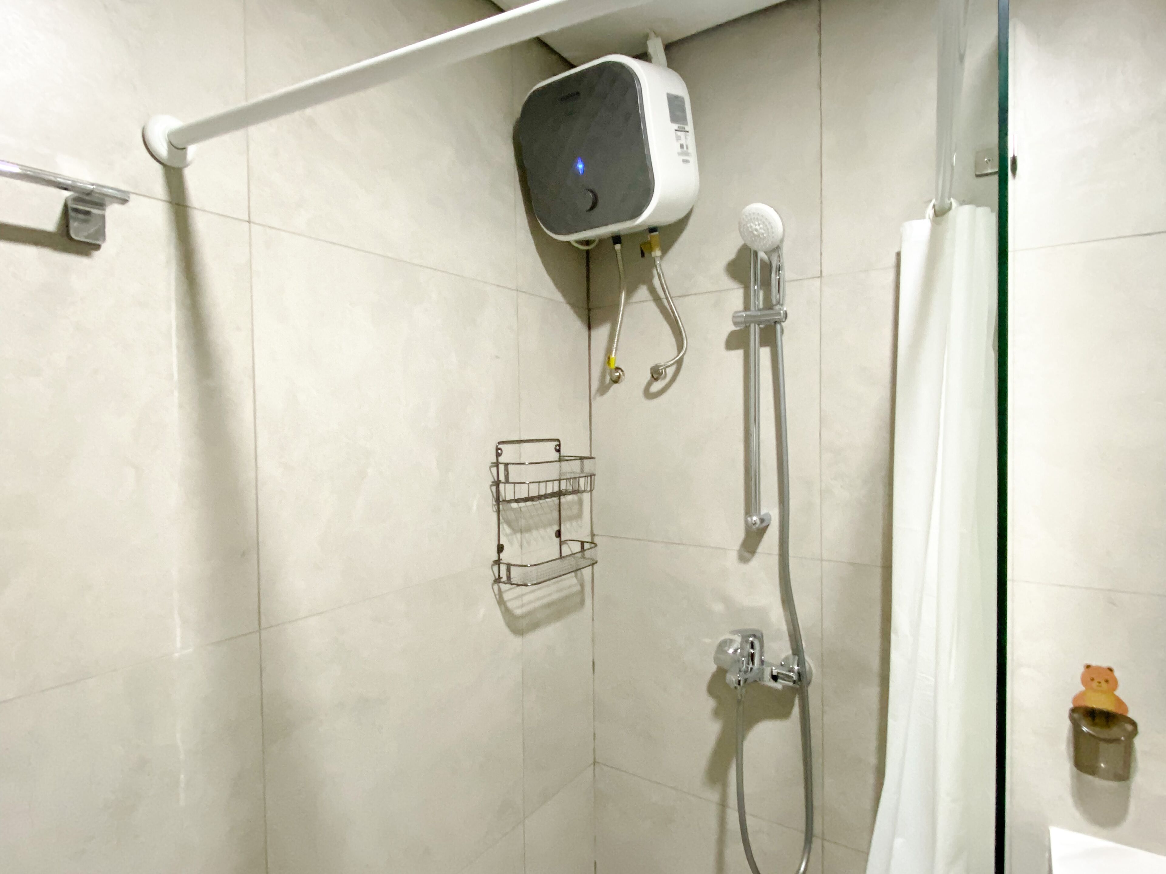 Un espace douche équipé d’un pommeau de douche à main, d’un robinet mural et d’une petite étagère.