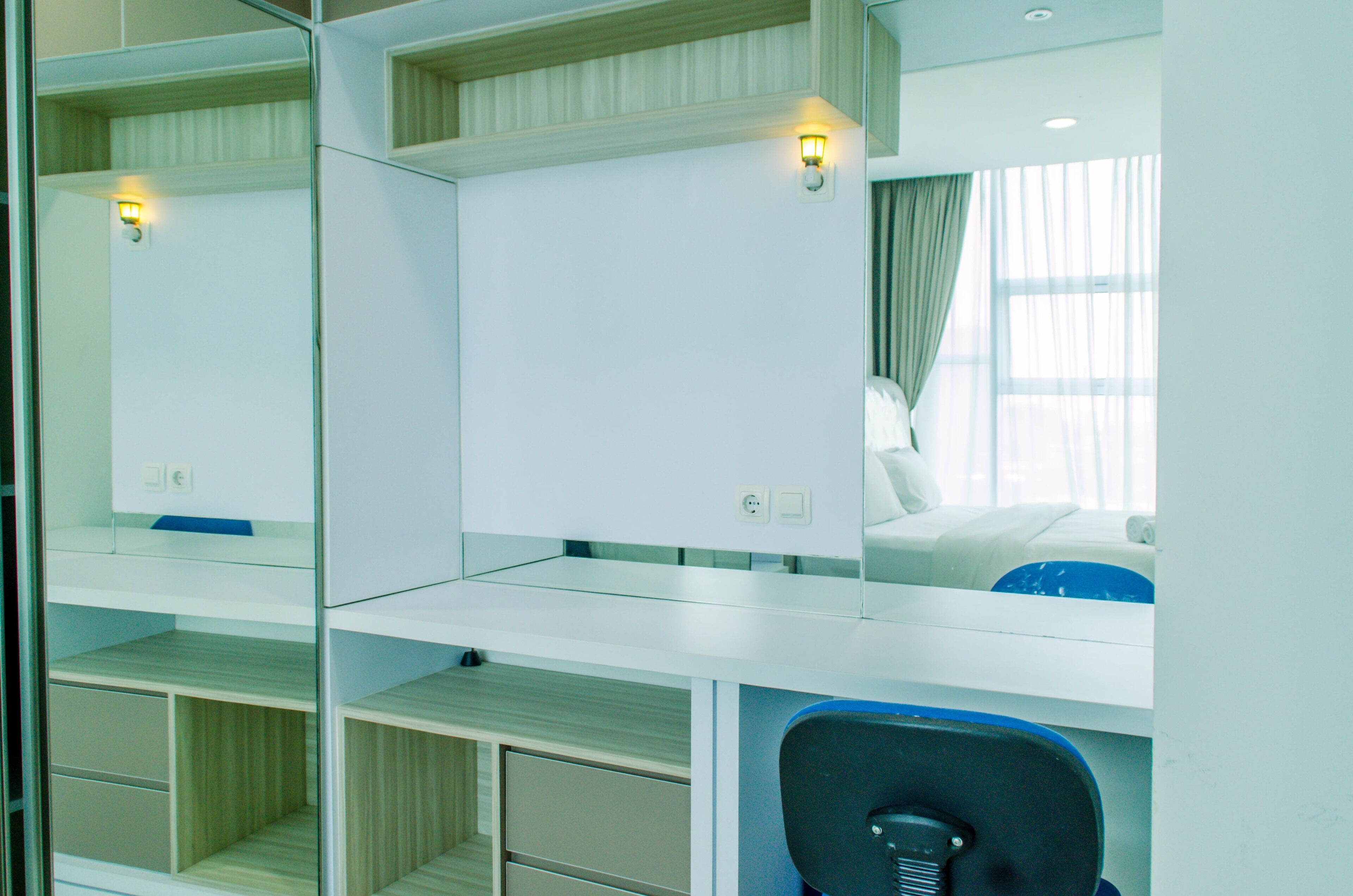 A hotel room with a mirrored wardrobe, a desk, and a bed.