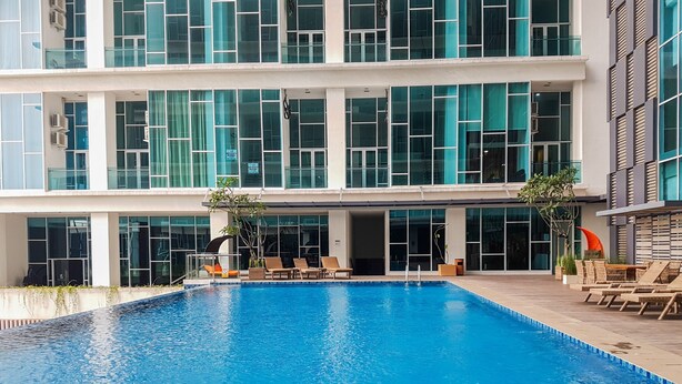 A modern building with a large indoor swimming pool, multiple lounge areas, and large windows. - Comfort 1Br At Brooklyn Alam Sutera Apartment (South Tangerang)