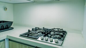A kitchen with a gas stove, a sink, and a blue colander on the countertop. - Comfort 1Br At Brooklyn Alam Sutera Apartment (South Tangerang)
