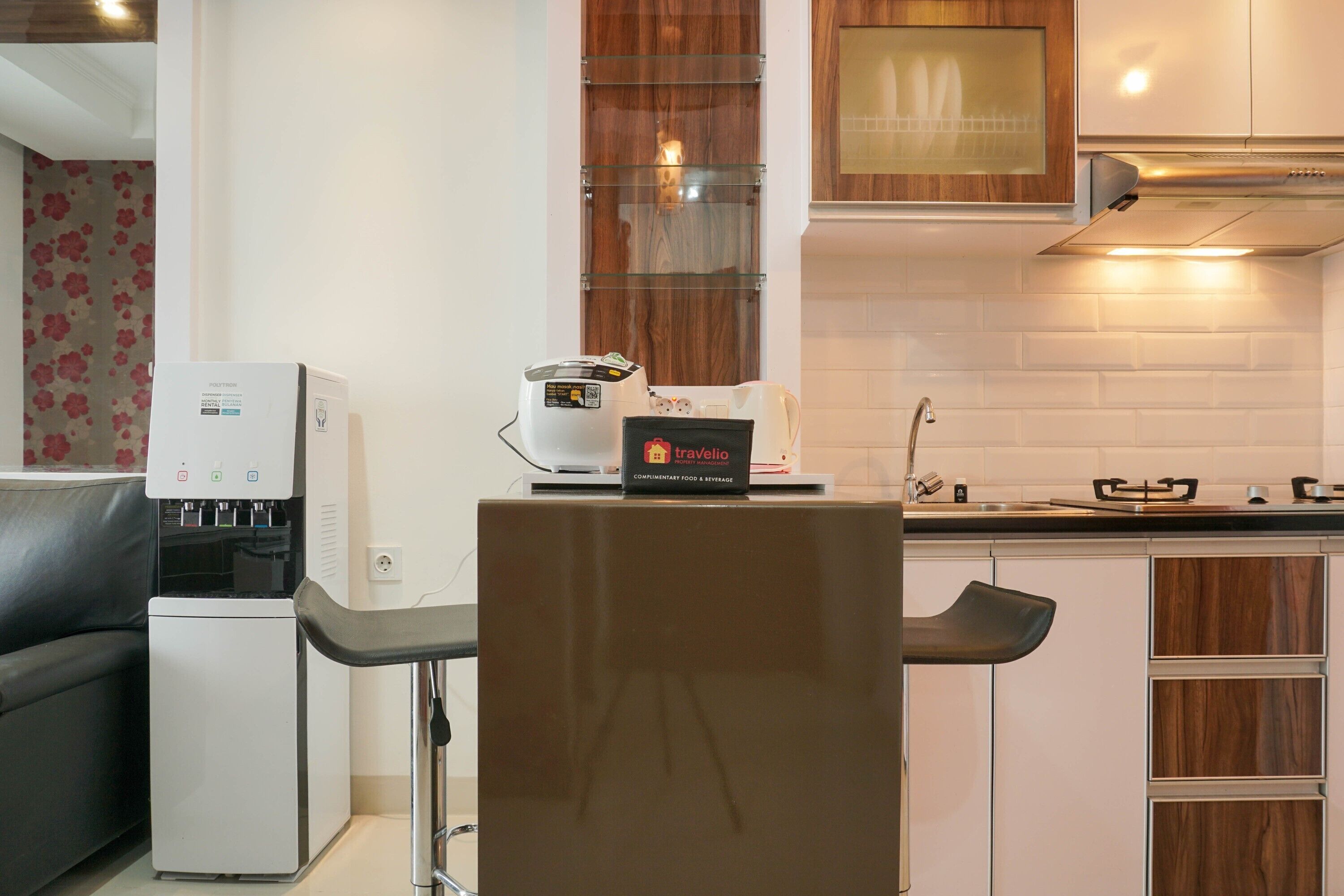 A modern kitchen with a coffee machine, a water dispenser, and a sign for complimentary food and beverage.