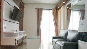 Ein modernes Wohnzimmer mit Flachbildfernseher an der Wand, einem Glastisch, einer Ledersofa und einem integrierten Kühlschrank.