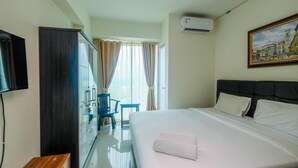 A hotel room with a bed, a TV, a desk, and a chair. - Spacious 1Br At Grand Kamala Lagoon Apartment (Bekasi)