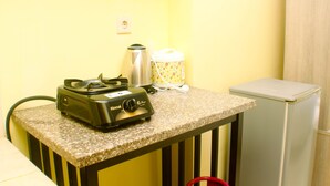A kitchenette with a coffee maker, a kettle, a small refrigerator, and a trash bin. - Warm And Homey Studio Room At Maple Park Sunter Apartment (Jakarta)