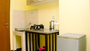 A compact kitchen with a countertop, a coffee maker, a kettle, and a refrigerator. - Warm And Homey Studio Room At Maple Park Sunter Apartment (Jakarta)