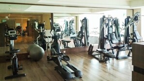 Une salle de sport équipée de divers appareils d’exercice, notamment des tapis de course, des vélos d’appartement et des appareils de musculation.